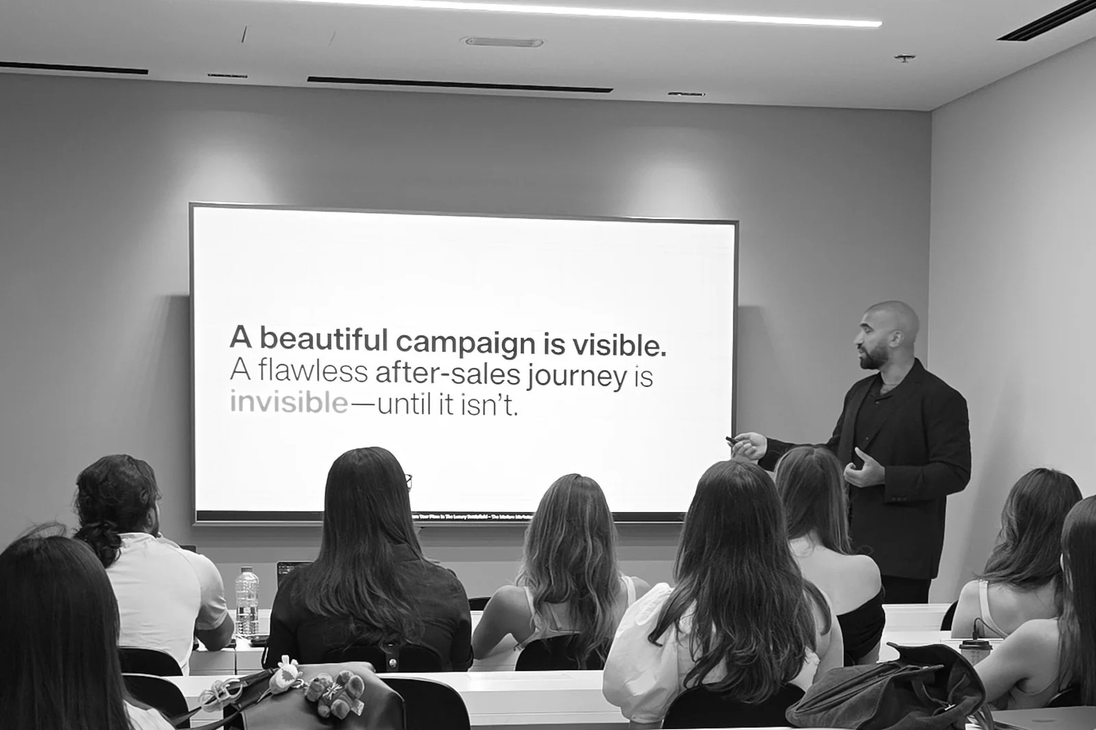 Ahmed El-Gamal presenting to a seated class beside a slide about campaigns and the after sales journey