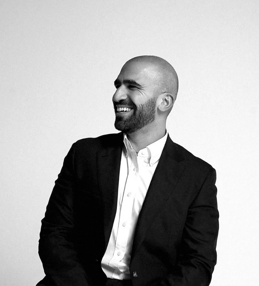 Ahmed El-Gamal laughing, in a dark jacket and white shirt