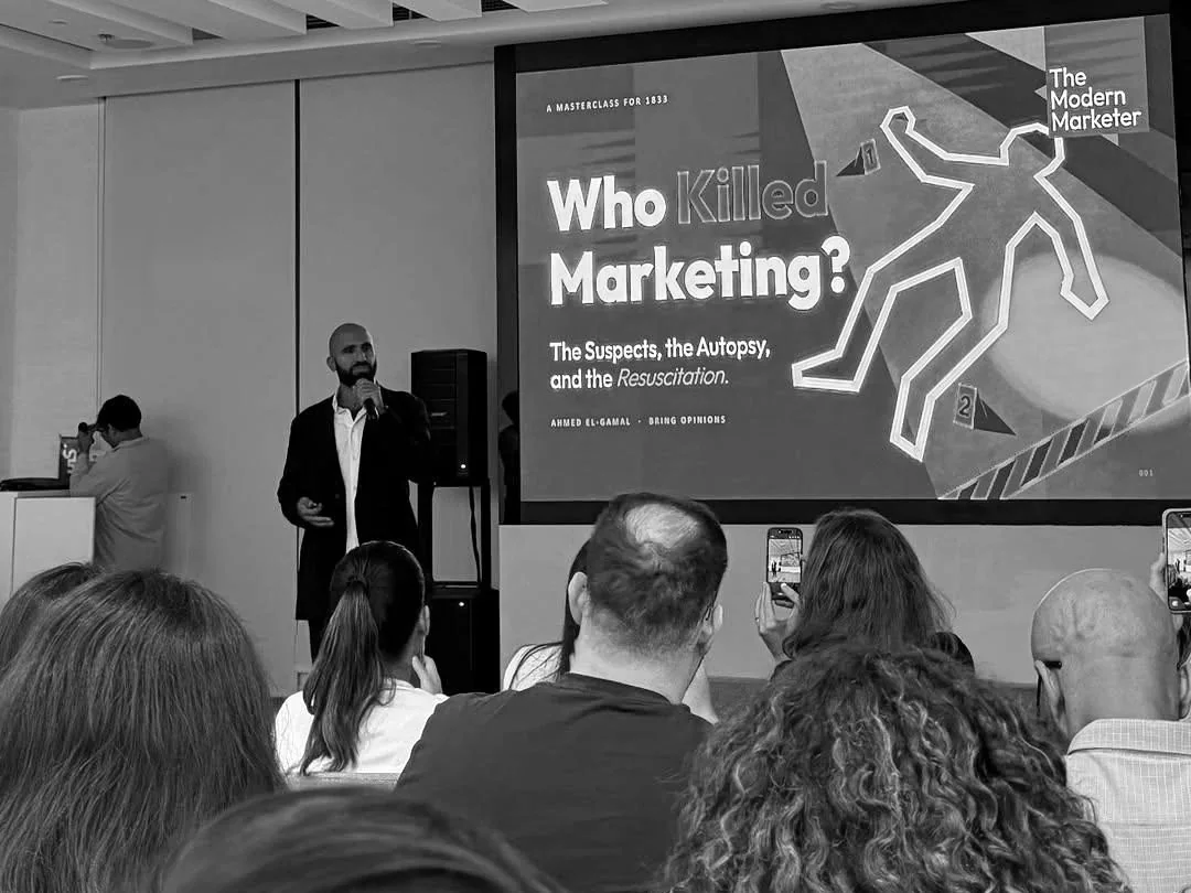 Ahmed El-Gamal presenting the Who Killed Marketing masterclass to a full room, the title slide on the screen behind him